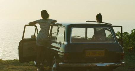Fototapeta premium Friends, women and view of beach on road trip with travel adventure, bonding and summer memory. People, back or ocean scenery on weekend vacation, holiday or journey for sightseeing or explore by car