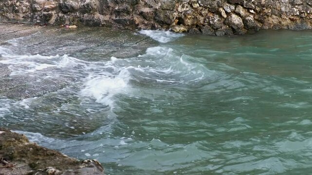 Waves rolling toward a concrete sloping boat dock, close up 