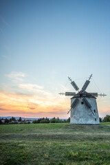 Windmill with wooden wings in a landscape setting. Fields, meadows and flowers appear in the sunset. Landscape shot in nature with a mill. historically untypical for the Balaton region in Hungary