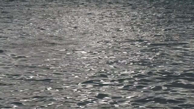 Wide shot of ripples and waves in the sea at twilight, steady footage