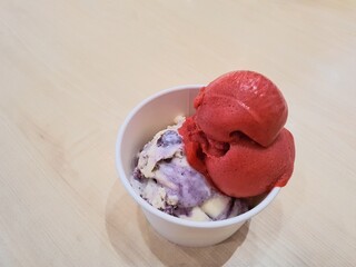 Ice cream and sorbet in the cup. Tasty ice cream and raspberry sorbet in the cup on a wooden table