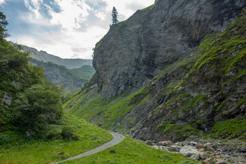 Serene hiking path on valley bottom by rocky mountain stream, Swiss Alps