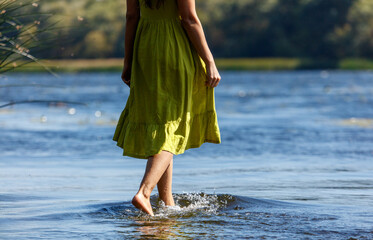 A woman in a green dress is walking in the water