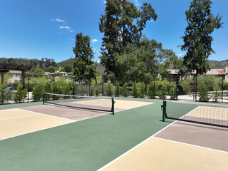 Obraz premium Aerial view of a pickle ball complex with courts beside a playground in a suburban park in San Diego