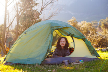 happy smiling child sitting in a tent against the backdrop of the mountains. child in a tent. ...