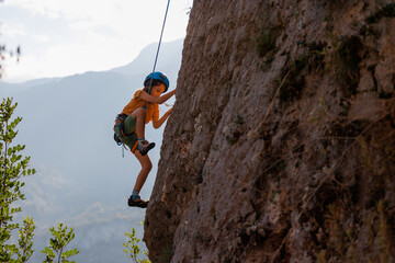 climber boy. the child trains in rock climbing. cute teen kid climbing on rock with insurance, lifestyle sport people concept.