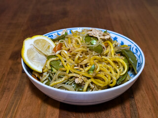 Filipino pancit with lemon on a wooden table.