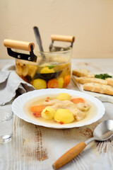 Delicious homemade fish soup with vegetables served on a plate alongside crusty bread