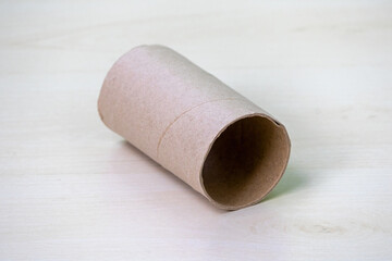 A single, empty toilet paper roll core rests on a wooden surface.