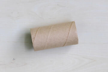 Top view of an empty toilet paper roll core rests on a wooden surface.