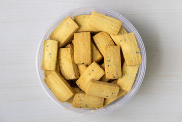 Top view of delicious, soft black cumin biscuits in a plastic container.