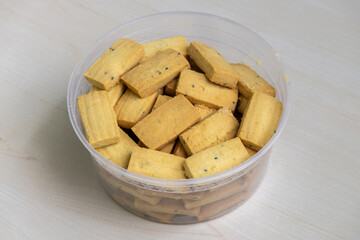 Delicious, soft black cumin biscuits, displayed on a wooden surface in a plastic container.