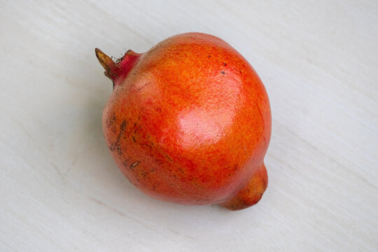 A ripe pomegranate (Punica granatum) on a light wooden background. Top view.