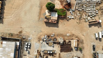 Aerial View of a Winding Dirt Road with Precast Concrete Materials and Scattered Trees
