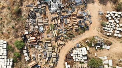 Top-Down Aerial Shot of a Dirt Road Surrounded by Disorganized Construction Materials