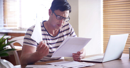 Man, documents and laptop in home for taxes, finance and writing with info for compliance in...