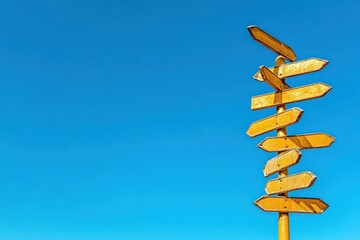 A weathered wooden signpost with multiple directional arrows against a clear blue sky.