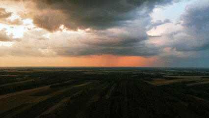 Colorful sunset with heavy clouds over fields before rain