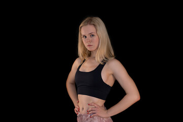 Serious Fit Blonde Girl in Sportswear with Hands on Hips on Black Background