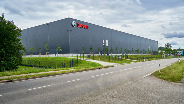 An industrial building, Logistics warehouse with the &lsquo;BOSCH&rsquo; logo, surrounded by lush greenery and a road, showcasing the blend of industry and nature. Wernau, Germany.