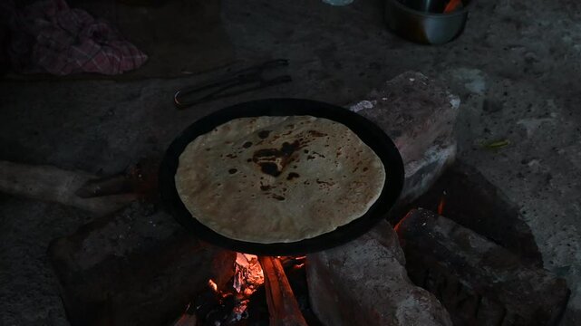 A village woman makes bread on the stove. cooking bread in clay stove , chula , makeing bread , roti , in village
