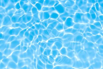 Blue water with ripples on the surface. Defocus blurred transparent blue colored clear calm water surface texture with splashes and bubbles. Water waves with shining pattern texture background.