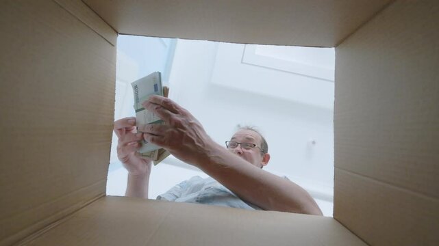 Man finds money in a box, taking it with happiness and curiosity, expressing delight in 4K slow motion 120fps