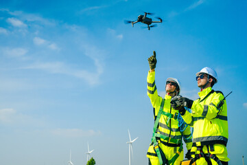 An engineer wearing safety gear closely inspects the base of a wind turbine in a renewable energy field.