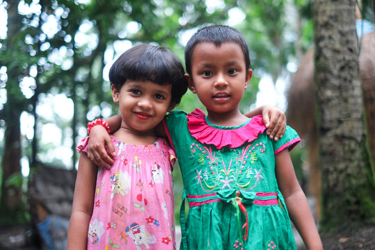 South asian little sisters standing together in outdoor wearing colourful dresses 
