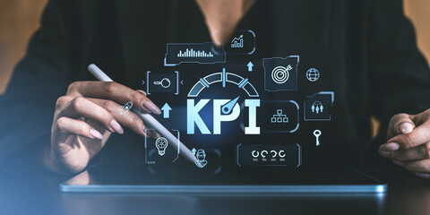 Close-up of hands holding a stylus with KPI graphics on a digital screen, illustrating business performance tracking and strategy concept.