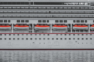 Close up detail view of side hull of modern cruiseship cruise ship liner Victory with porthole windows, life boats and railing