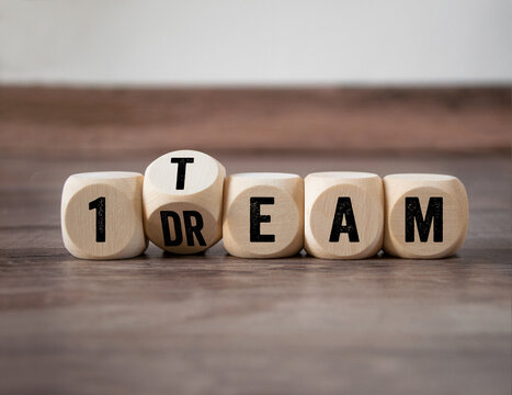 Cubes, dice or blocks with dreamteam or dream team on wooden background