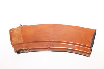 A curved magazine for a firearm is placed on a neutral surface, showcasing its design and color. The magazine appears well-used, indicating prior activity.