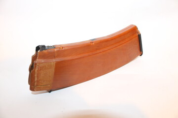 A large ammunition magazine rests flat on a plain background. The magazine has a distinct color and shape, designed for storing multiple rounds of ammunition.