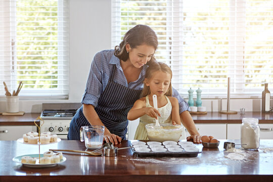 Mom, girl and baking support in kitchen with learning, culinary skills or teaching muffin recipe. Family, woman and kid with ingredients preparation for cooking, bonding and child development in home