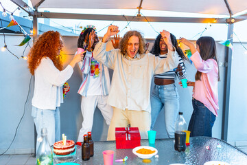 Multi-ethnic friends dancing celebrating birthday party at terrace