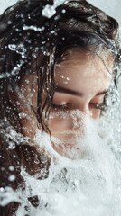 Close-up of a woman's face enveloped in cascading water, capturing serenity and freshness in motion.
