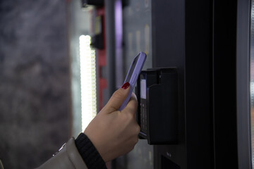 Close-up view of woman paying for purchase at free standing coffee vending machine using...
