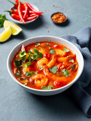 Tom Yum, spicy thai asian soup with prawns in a grey bowl. Grey background. Close up.