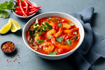 Tom Yum, spicy thai asian soup with prawns in a grey bowl. Grey background. Close up.