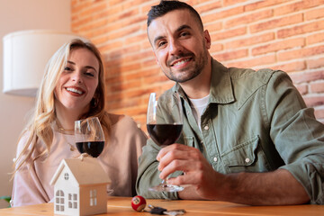 A joyful couple toasts with red wine, smiling and enjoying a warm moment together in a cozy indoor setting. The image conveys celebration, connection, and relaxation in a casual atmosphere.