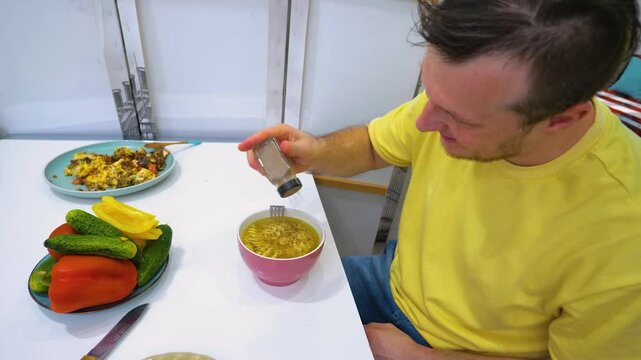 A young man eats doshirak noodles, a pasta dinner in chicken gravy, slow motion. Hot dish of food
