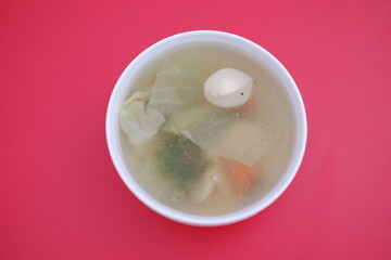 A bowl of soup on a red table