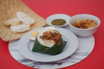 rice with meat, egg, crackers, sambal and noodles on a red background