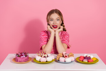 Charming young woman in pink setting enjoys sweet treats with stunning beauty and joyful expression