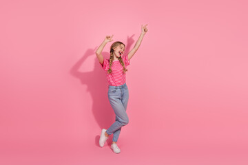 Young woman in casual outfit enjoying and posing against a vibrant pink background, radiating joy and charm, wearing a striped t-shirt.