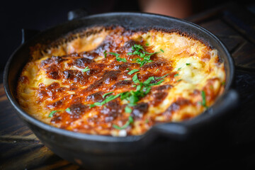 Baked lasagna with cheese and green herbs served in the cast iron skillet