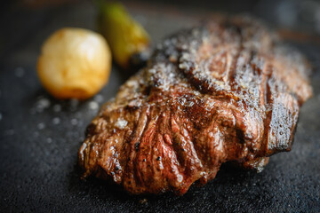 Beef stake with potatoes and chili pepper served on the black skillet