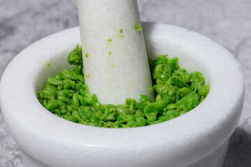 homemade mushy peas in a white granite stone pestle and mortar. Traditional British food concept.