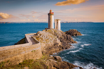 un phare côtier sur un rocher, avec une mer agitée © Quentin